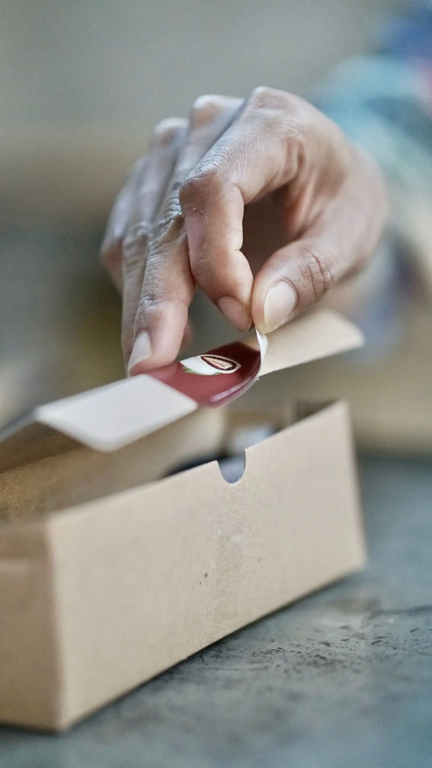 Mano colocando una etiqueta sobre una caja de cartón